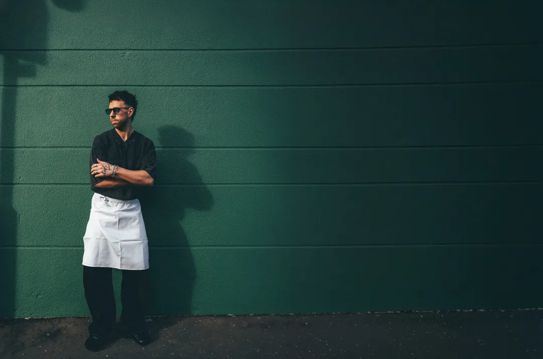 Nathan Snow, founder of Food Story Media, arms folded in a chef's apron against a green wall